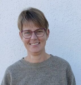 Smiling person with glasses and sweater