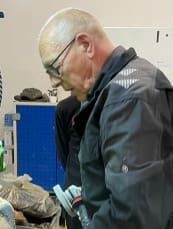 Man with glasses leaning over workbench